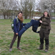 Preisübergabe für: Engagement plus Losglück Zwei Frauen stehen auf einer Wiese mit Fluss im Hintergrund und halten zwischen sich eine blaue Hose.